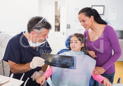 Pediatric dentist explaining to young patient and her mother the