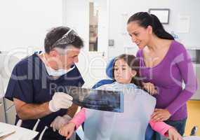 Pediatric dentist explaining to young patient and her mother the