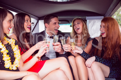 Happy friends drinking champagne in limousine