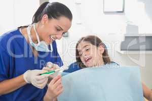 Smiling pediatric dentist explaining to young patient the toothb