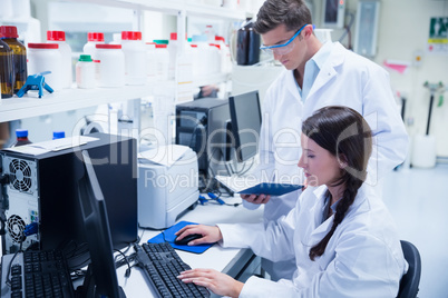 Chemist team working together at desk using computer