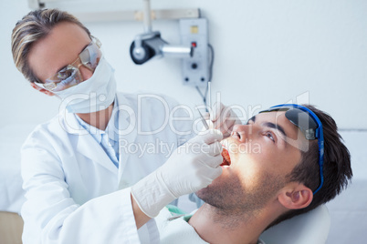 Female dentist examining mans teeth