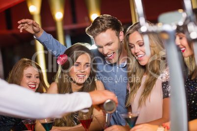 Drunk friends watching barman pouring cocktail