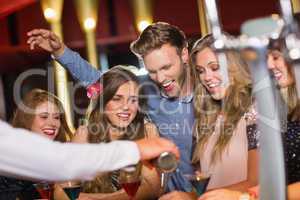 Drunk friends watching barman pouring cocktail