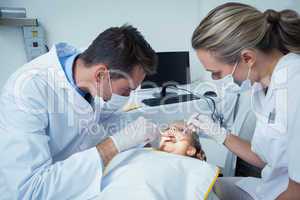 Dentist examining girls teeth with assistant