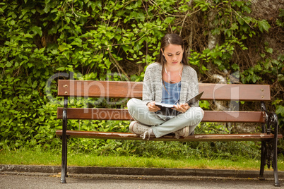 Student sitting on bench listening music with mobile phone and r