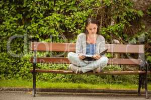 Student sitting on bench listening music with mobile phone and r