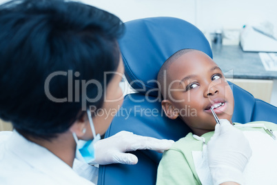 Dentist examining boys teeth in dentists chair
