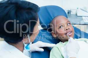 Dentist examining boys teeth in dentists chair