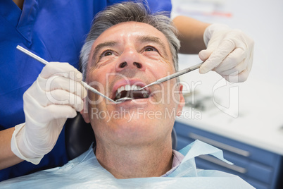 Dentist examining a patient with tools