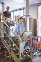 Young men carrying keg smiling at camera