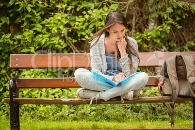 Smiling student sitting on bench reading book