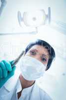 Female dentist in surgical mask holding dental drill