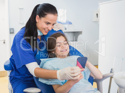 Pediatric dentist and young patient holding a mirror