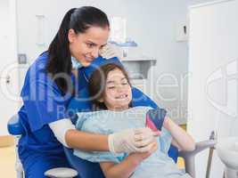 Pediatric dentist and young patient holding a mirror