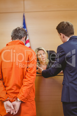 Lawyer and judge speaking next to the criminal in handcuffs