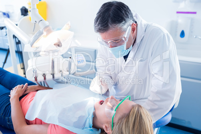 Dentist examining a patients teeth in the dentists chair