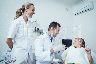 Male dentist  and assistant talking to girl