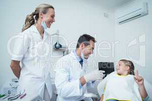 Male dentist  and assistant talking to girl