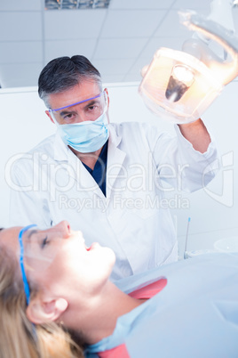 Dentist examining a patients teeth in chair under bright light