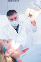 Dentist examining a patients teeth in chair under bright light