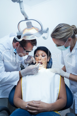 Dentist with assistant examining womans teeth