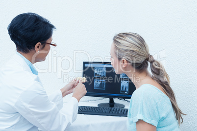 Dentist showing woman her mouth x-ray on computer