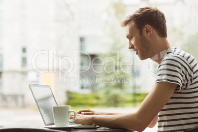 Smiling student using laptop in cafe