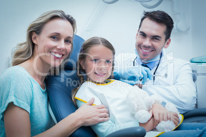 Dentist examining girls teeth with assistant