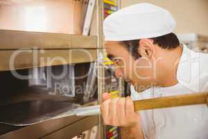 Baker taking bread out of oven