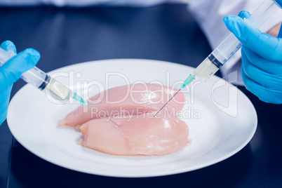 Food scientist injecting raw chicken