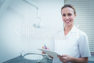 Smiling female dentist holding clipboard