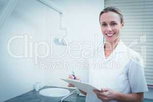 Smiling female dentist holding clipboard