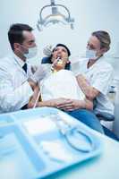 Dentist with assistant examining womans teeth
