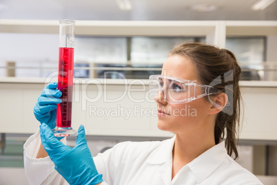 Young pharmacist holding beaker of red liquid