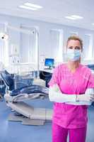 Dentist in pink scrubs standing with arms folded