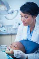 Female dentist examining boys teeth