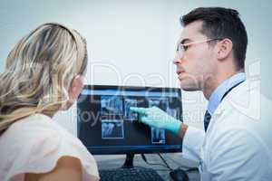Dentist showing woman her mouth x-ray on computer