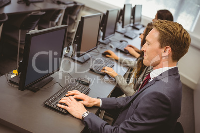 Three focused people working in computer room