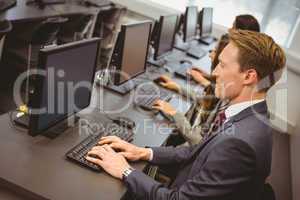 Three focused people working in computer room