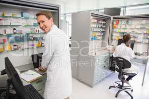 Happy pharmacist using the computer