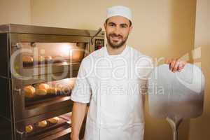 Baker smiling at camera beside oven