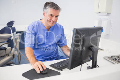 Portrait of a happy dentist using computer