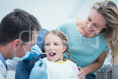 Dentist examining girls teeth with assistant