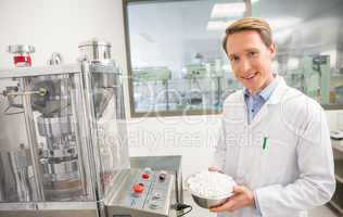 Happy pharmacist showing bowl of pills