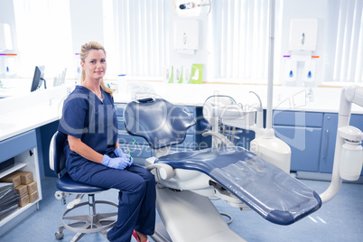 Dentist smiling at camera beside chair