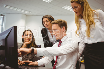 Casual business team working together at desk using laptop