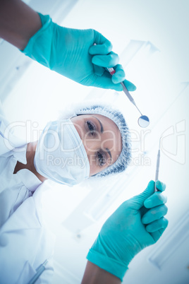 Female dentist in surgical mask holding dental tools