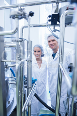 Scientist team behind metal gauge looking at camera