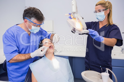 Dentist doing injection to his patient and nurse adjusting the l